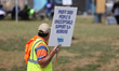 Dockworkers and their supporters hold signs during a strike outside the Bayport Container...