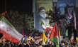 Iranians wave Iranian and Palestinian flags under a giant portrait of Lebanon's Hezbollah...