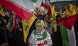 An Iranian woman wearing an Iranian flag looks on while taking part in a gathering marking...