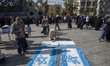An Iranian man prepares Israeli flags to be set on fire during a gathering marking the mem...