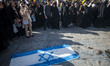 Veiled Iranian women stand next to an Israeli flag that is prepared to be set on fire duri...