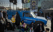 Veiled Iranian women sit under a portrait of Lebanon's Hezbollah Secretary General Hassan...