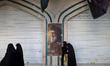 Veiled Iranian women walk past a portrait of Lebanon's Hezbollah Secretary General Hassan...