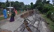 People stand near the erosion caused by the Kopilli River on a section of the PWD road nea...