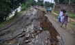 People stand near the erosion caused by the Kopilli River on a section of the PWD road nea...