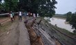 People stand near the erosion caused by the Kopilli River on a section of the PWD road nea...