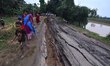 People stand near the erosion caused by the Kopilli River on a section of the PWD road nea...