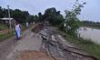 People stand near the erosion caused by the Kopilli River on a section of the PWD road nea...