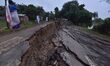 People stand near the erosion caused by the Kopilli River on a section of the PWD road nea...