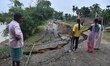 People stand near the erosion caused by the Kopilli River on a section of the PWD road nea...