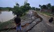 People stand near the erosion caused by the Kopilli River on a section of the PWD road nea...