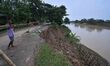 People stand near the erosion caused by the Kopilli River on a section of the PWD road nea...