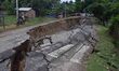 People stand near the erosion caused by the Kopilli River on a section of the PWD road nea...