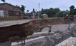 People stand near the erosion caused by the Kopilli River on a section of the PWD road nea...