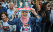 A woman shouts slogans against President Kais Saied as she raises a portrait of the impris...