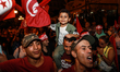 Kais Saied's supporters wave national flags of Tunisia as they celebrate after unofficial...