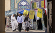 Two veiled Iranian women and a man walk past Lebanon's Hezbollah flags in a holy shrine in...