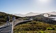 Tourists walk along a scenic pathway near a bridge on the Atlantic Ocean Road in Norway, o...