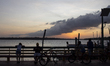 People and their bicycles watch the sunset on the banks of the Amazon River in Afua, Para,...