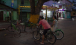 People and their bicycles are in the town square at night on the banks of the Amazon River...