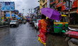 A woman holds an umbrella while walking on the street during rain due to Cyclone Dana in K...
