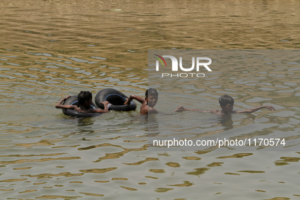 Village children floats in the water of an irrigation canal by the help of air filled tube as they are playing in the water to beat the heat...