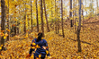 A woman throws leaves in the air in a forest during the autumn season in Maple, Ontario, C...