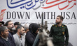 An Islamic Revolutionary Guard Corps (IRGC) military personnel stands in front of an anti-...