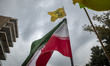 A demonstrator (not pictured) waves an Iranian flag and a flag of Lebanon Hezbollah while...