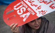 An Iranian woman holds an anti-U.S. placard while participating in an anti-U.S. and anti-I...