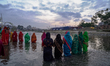 Hindu devotees perform rituals and offer prayers to the rising Sun God on the banks of the...