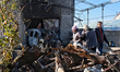 People stand near a garage with a car destroyed by a large-scale Russian missile strike in...