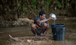A tribal man collects water from the reservoir, locally known as ''Jhiri,'' in Durgapur, N...