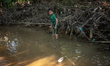 Indrajit (11) catches fish from the reservoir with a small net to support his family in Du...
