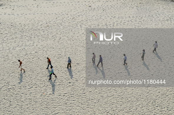 Indians walk on sand,the dried and shrinked River bed of Ganges river,during a hot day in Allahabad on April 28,2016.The drought has affecte...