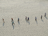 Indians walk on sand,the dried and shrinked River bed of Ganges river,during a hot day in Allahabad on April 28,2016.The drought has affecte...