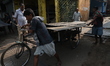 Labourers pull a cycle rickshaw loaded with iron plates at a wholesale iron market in Kolk...
