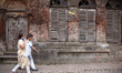A woman speaks on her mobile phone as she walks past an abandoned temple near a steel and...