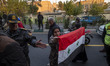 A female Iranian protester holds a flag of Syria while participating in a protest against...
