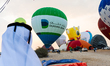 People watch as hot air balloons take off during the Qatar Balloon Festival 2024 in Doha,...