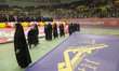 Young veiled Iranian schoolgirls walk past a logo of the IRGC after performing in a ceremo...
