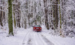 A car drives through a snow-covered forest road that road services cannot reach to clear t...