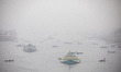 Boats and bulkheads cross the Buriganga River in densely foggy weather in Dhaka, Banglades...