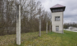 An electrified fence and watchtower of the Dachau concentration camp in Dachau, Germany, o...