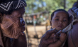 Old woman plays with a baby in the Living Museum of the Ju’Hoansi-San, Grashoek, Namibia 