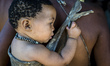 Mother with child on her back in the Living Museum of the Ju’Hoansi-San, Grashoek, Namibia...