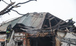 Firefighters work on the smoking roof of a house partially destroyed by a Russian drone st...