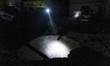 Torchlight illuminates the crater from falling missile debris in the Obolonskyi district a...