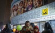 A young Iranian woman uses her iPhone while holding donated sweets during a religious fest...