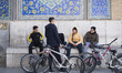 Young Iranian men sit together next to their bicycles outside a historical mosque in Naqsh...